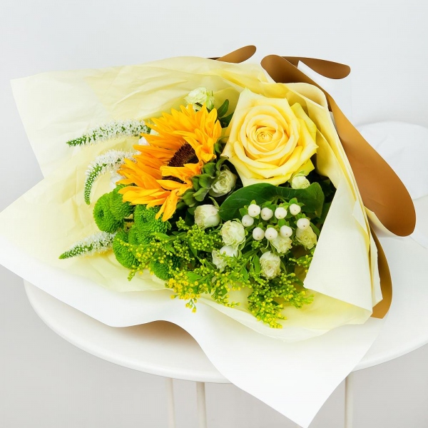 Sunflower - 1, Yellow rose 50 cm - 1, Spray rose: white, cream, light pink 50 cm - 3, Athos poms Green Lizard - 1, Santini White Spray Chrysanthemum - 2, Solidago (1 pc.), Hypericum, Veronica spray, Pistachio, Wrapping Paper