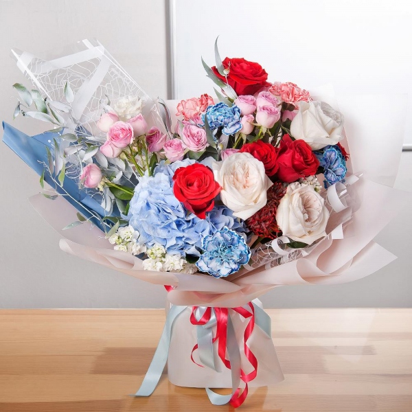 Bright pink spray rose mix, 50 cm - 4, Blue/purple hydrangea - 1, Blue carnation - 5, White Matthiola - 4, Red rose Nina 50 cm - 9, Peony style roses - 4, lisianthus - 2, Orange carnation - 5, Nutan, Ruscus italian, Wrapping Paper