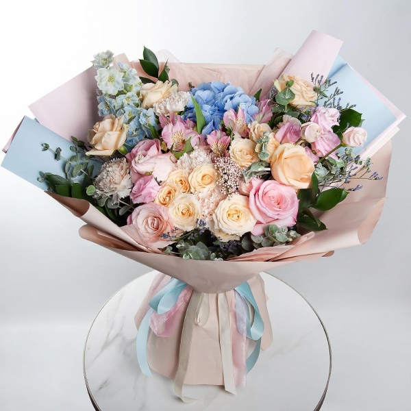 Blue/purple hydrangea - 1, Pink rose 50 cm - 4, Spray rose: white, cream, light pink 50 cm - 3, Rose Cream 50 cm - 5, Alstromeria white, soft pink - 4, Carnation white, cream - 7, Pink Lisianthus (Eustoma) - 2, Ozotamnus, Limonium (1 pc.), Blue Delphinium, Ruscus, Eucalyptus, Wrapping Paper