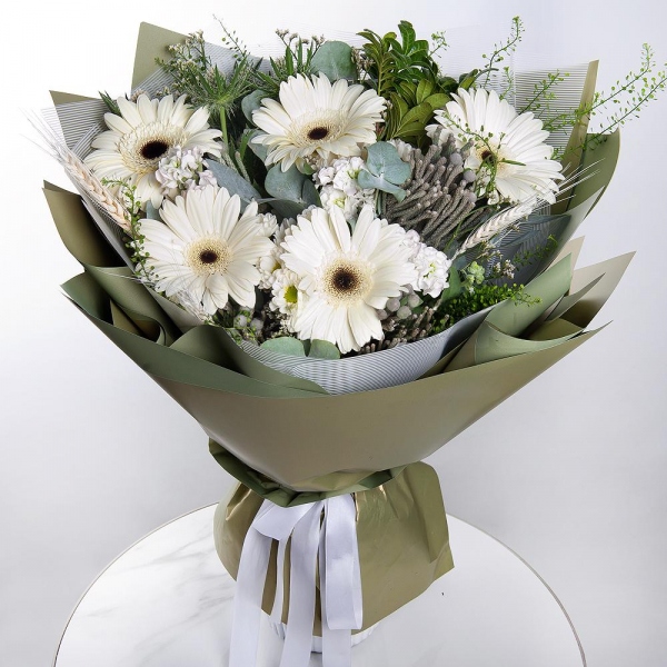 Gerbera white - 9, White Matthiola - 3, Pistachio, Eucalyptus, Brunia Green Lanuginosa (1 pc.), Eryngium, Green bell (1 pc.), Dried flowers in assortment, Wrapping Paper